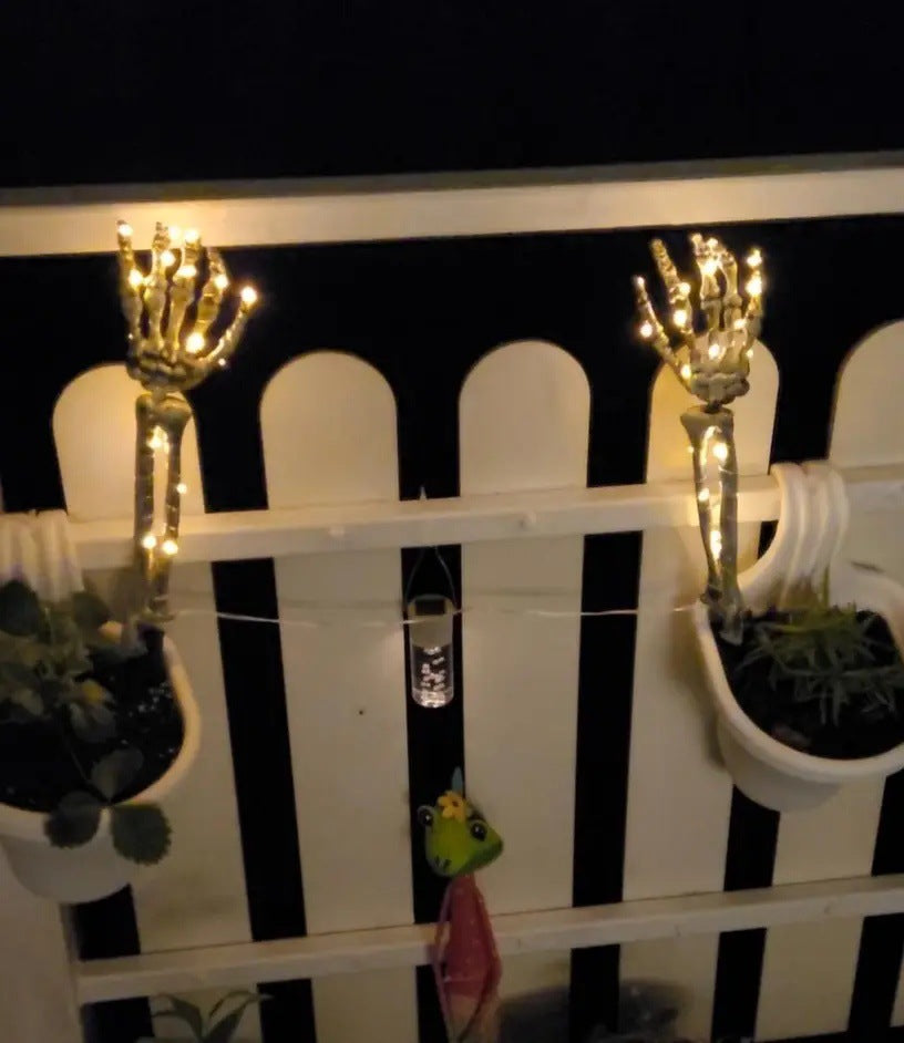 Solar-powered glowing skull arm garden stake light